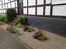 Staudenbeete eingefasst mit Klinker in wassergebundener Wegedecke im Eingangsbereich eines Fachwerkhauses in Lichtenau.