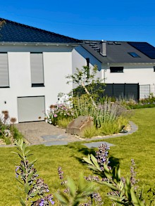 Garten in Lichtenau mit Rasenfläche, Natursteinfindlingen und Beeten mit Stauden und Solitärgehölzen.