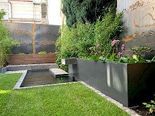 Minigarten in Paderborn mit formalen Wasserbecken, Hochbeet und Wasserschütte aus Metall.