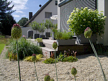Holzterrasse mit Kübelbepflanzung und angrenzendem Kiesbeet mit in einem Garten in Paderborn.