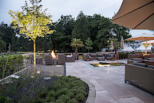 Elliptisches Staudenbeet mit beleuchtetem Baum und trockenheitsverträglichen Stauden auf einer Hotelterrasse in Bad Lippspringe.