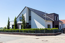 Privatgarten in Salzkotten eingefasst mit Metallzaun und Eibenhecke sowie Säulenbuchen als Sichtschutz.
