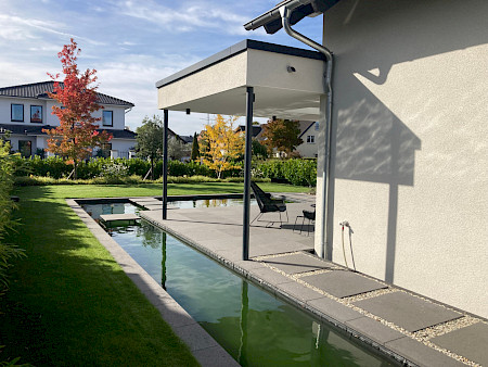 Formaler Bachlauf in einem Hausgarten in Paderborn mit Schrittplatten im Wasser und entlang des Hauses.