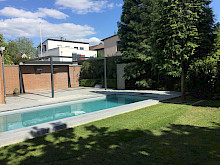 Pool in einem Garten in Paderborn mit Einfassung aus Granit sowie angrenzender Terrasse mit Überdachung.