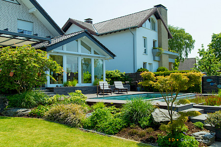 Hausgarten in Lichtenau mit einem Pool in Sichtbeton gefertigt und einer Bepflanzung aus Gehölzen und Stauden.
