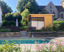Pool in Lichtenau mit Trockenmauern und Treppen aus Naturstein sowie einem Gartenhaus aus Holz und bunter Staudenbepflanzung.