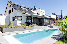 Pool in einem Hausgarten in Salzkotten mit Unterflurrolladenabdeckung. Pooleinfassung sowie Treppe sind aus Granit. Das angrenzende Hochbeet ist aus Stahl.