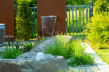 Privatgarten in Borchen mit zwei Wasserspielen. Ausgebildet als Quellstein in Grauwacke und einer Cortenstahltafel mit intergrierter Wasserschütte aus Edelstahl.
