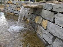 Teich mit angrenzender Trockenmauer und ausgebildetem Wasserfall aus Tudorfer Natrustein in Salzkotten.