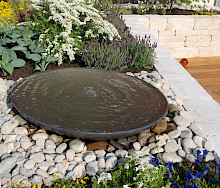Ausstellunggarten im Kloser Dalheim in Lichtenau mit Hochbeeten aus Naturstein und einer Wasserschale aus Metall.