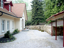 Einfahrt aus Großpflaster in Sandstein mit einer angrenzenden Trockenmauer.