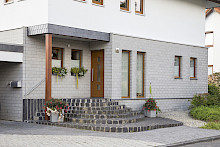 Treppenanalge vor einem Eingang eines Hauses in Lichtenau aus Basaltgroßpflaster in geschwungener Form versetzt. Die angrenzende Einfahrt ist mit Betonpflaster gepflastert.
