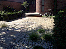 Vorgarten in Paderborn mit Pflasterng und Treppe aus Porphyr, sowie einem mit Gräsern bepflanzten Kiesbeet aus Lippekies.