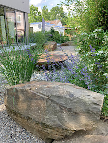Findlinge aus Grauwacke in einem Garten in Paderborn, bepflanzt mit Gräsern, Bambus und Stauden.