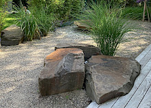 Garten in Paderbron mit Grauwackefindlingen, die teileweise in die Holzterrasse eingelassen sind.