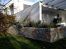 Trockenmauer in einem Hausgarten in Paderborn aus Natrustein, bepflanzt mit diversen Kräutern.