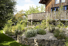 Naturnaher Garten eines Holzhauses in Borchen mit einer Natursteinmauer aus Sandsteinfindlingen.