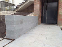 Eingangsbereich eines Hauses mit Granitplatten gepflastert und einer angrenzenden Mauer aus Granitblockstufen.