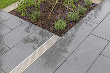 Detail einer Terrasse in Paderborn, die aus Granitplatten gepflastert wurde und eine Rinne aus Edelstahl zur Entwässerung hat.