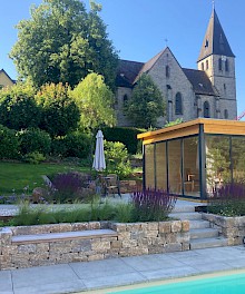 Poolgarten mit Trockenmauer aus Muschelkalk und großformatigen Betonplatten.