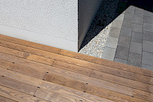 Detail eines Holzdecks mit angrenzendem Pflasterweg und Kiestraufe aus Lippekies.