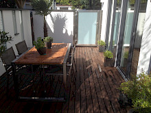Holzterrase umgeben von hellen Mauern in einem kleinen Stadtgarten in Paderborn.