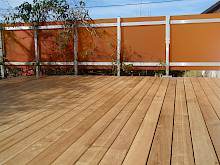 Holzterrasse in Lichtenau mit einem Sichtschutzzaun aus orangenem Glas.