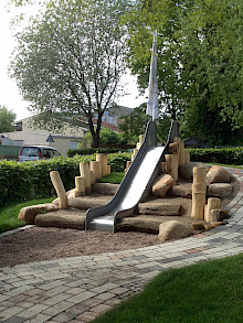 Hügel einer Rutsche in einem Kindergarten in Paderborn eingefasst mit Holzstämmen aus dauerhafter Robinie.