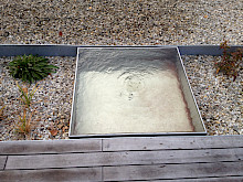 Modernes und quadratisches Wasserspiel aus Edelstahl in einem Garten in Paderborn.