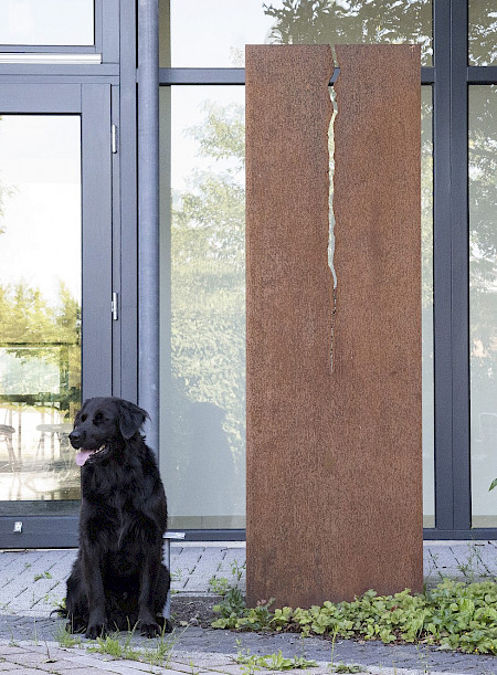 Kunstwerk aus einer Cortenstahlplatte mit einem mittig verlaufenden Riss am Technologiezentrum in Lichtenau.