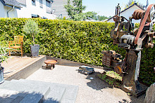 Maschinenskulptur aus Metall in einem Privatgarten in Paderborn mit einer grünen Hecke im Hintergrund.
