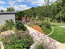 Weg in einem Privatgarten in Borchen, der sich durch ein hügeliges Beet zieht und dessen seiten mit Stahlwangen abgefangen werden.
