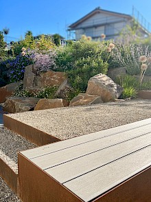 Indivduell gestaltete Treppe aus Cortenstahl mit integrierter Sitzbank und Findlingen aus Grauwacke.