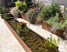 Individuell geplantes Wasserbecken mit angrenzender Wasserschütte aus Cortenstahl.