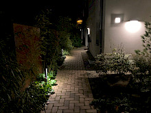 Pollerleuchten entlang eines Klinkerweges, der auf den Hauseingang eines Mehrfamilienhauses in Paderborn führt.