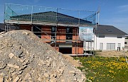 Haus im Rohbau mit extremer Hanglage und großem Erdhaufen auf dem Grundstück.